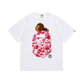 White graphic T-shirt, pink camouflage ape-head graphic with a small brown cartoon character, front view