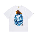 White graphic T-shirt, blue camouflage ape-head graphic with a small brown cartoon character, front view