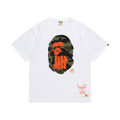 White graphic T-shirt, olive camouflage ape-head graphic with orange tally-mark design and orange lettering on front and back, front view