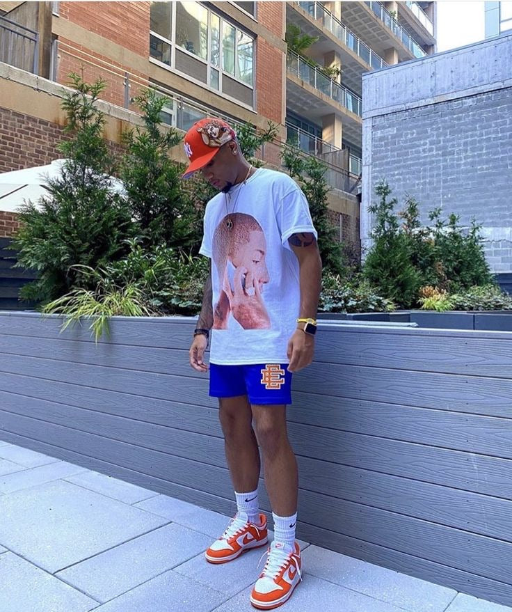 Royal blue graphic shorts styled with orange sneakers